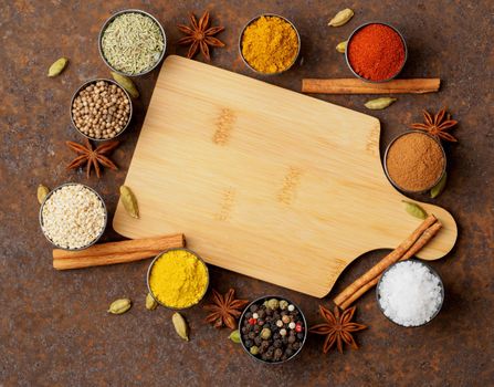 Various Indian spices in metal cups. Empty wooden Board, top view, space for text.