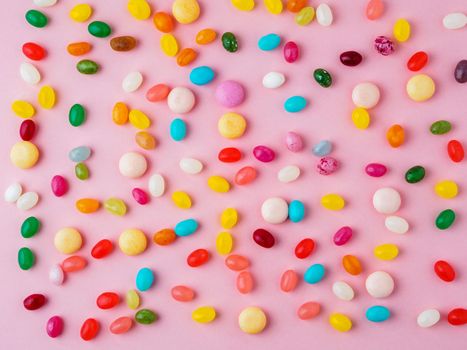 Many scattered colorful sweets, candies, lollipops on bright pink background, top view