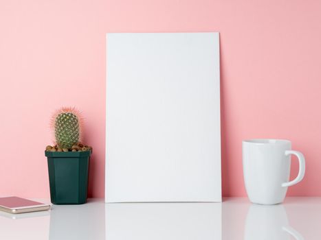 Blank white frame and plant cactus, cup of coffee or tea on a white table against the pink wall with copy space. Mockup with copy space.