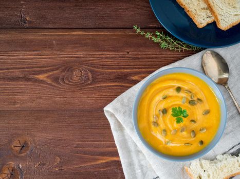 Dietary vegetarian pupmkin cream soup puree, on dark brown wooden table, top view, copy space, close up.