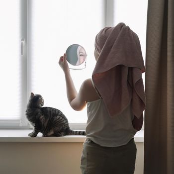 Young woman and her adorable cat at home. Lazy weekend at home with loved pet concept. Close up, copy space, interior background. Love, togetherness and pets indoors.