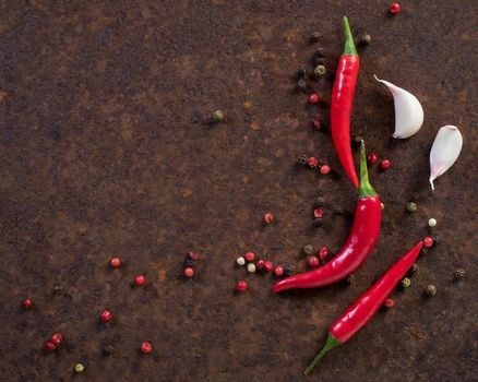 red hot chili pepper pods and peas, garlic clove on dark rusty metal background, top view, copy space