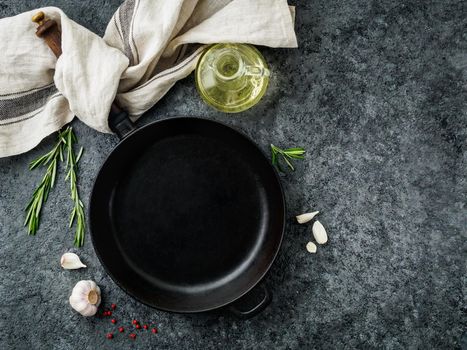 blank cast iron frying pan on dark grey concrete background, top view, blank space for text