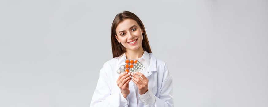 Pharmacy, healthcare workers, insurance and hospitals concept. Gorgeous doctor in white scrubs, female physician or pharmacist smiling, showing medicine, different pills or antibiotics.