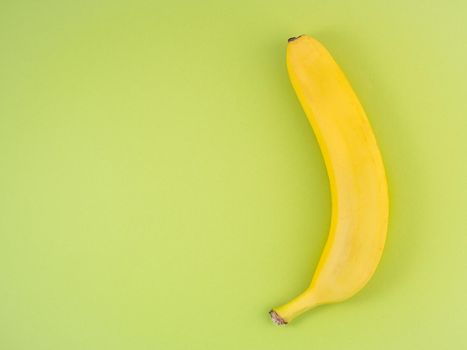 ripe yellow banana on bright green background with copy space.