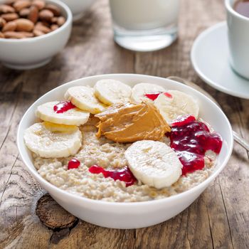 Healthy Breakfast in the morning - oatmeal with slices of bananas, raspberry jam and peanut butter. Side view.