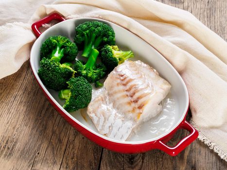 Fish cod baked in the oven with broccoli - healthy diet healthy food. Rustic wooden brown background, side view, selective focus.
