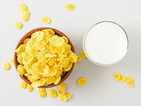 wooden bowl with dry cereal for breakfast, cup of milk, top view, gray background