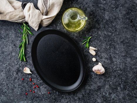 empty oval cast iron frying pan on dark grey concrete background, top view, blank space for text