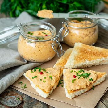 Fresh homemade chicken pate on a toasted bread over rustic background, side view