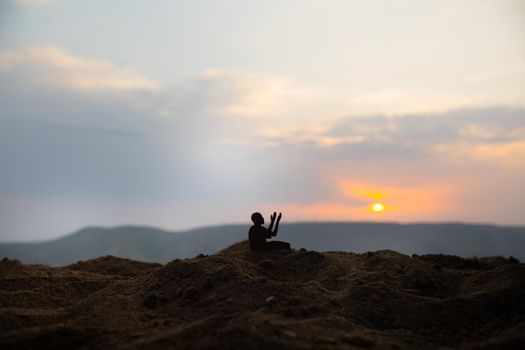 Silhouette of muslim prayer on sunset. Ramadan Kareem background. Praying people. Selective focus