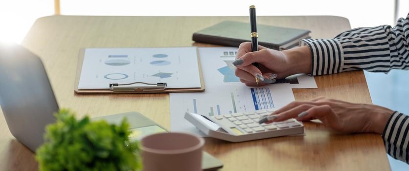 Close up Business woman using calculator for do math finance on wooden desk in office and business working background, tax, accounting, statistics and analytic research concept.