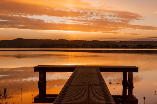 Surreal sunset views from a jetty on the lake backed by mountains.