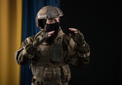 male soldier in a military uniform and helmet on the background of the national flag of Ukraine