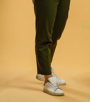 Inverted female legs in light trousers and sneakers.