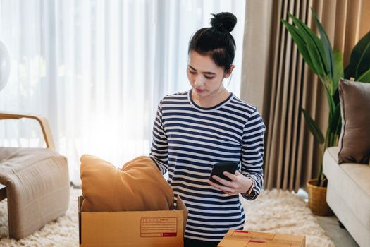 Online merchandising business idea, a beautiful girl is packing pillows in a shipping box to prepare to send items to customers according to orders received from customers