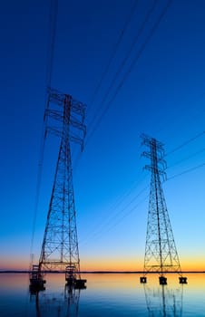 High voltage transmission lines crossing Wheeler Lake at dusk near Athens AL. Electricity pylons at sunset. Power and energy.