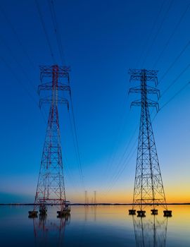 High voltage transmission lines crossing Wheeler Lake at dusk near Athens AL. Electricity pylons at sunset. Power and energy.