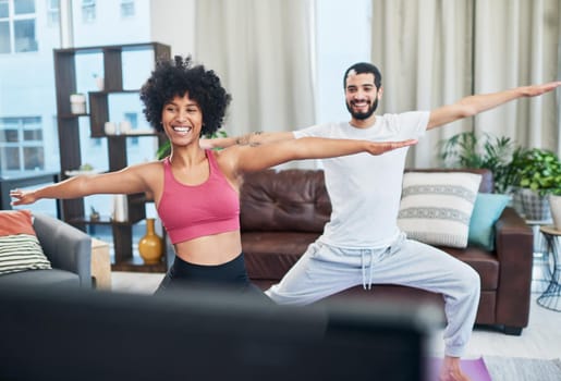 Shot of a couple looking at the television while practising yoga at home.