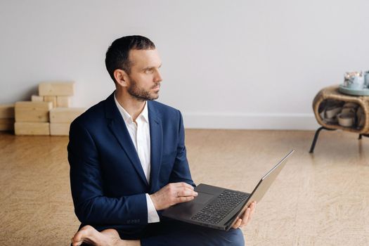 A man in a formal suit works sitting in a fitness room on a laptop.