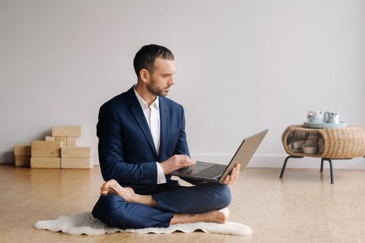 A man in a formal suit works sitting in a fitness room on a laptop.