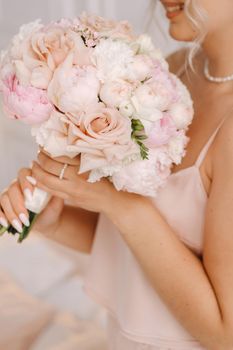 The bride holds a wedding bouquet of roses in her hands. Wedding floristry.