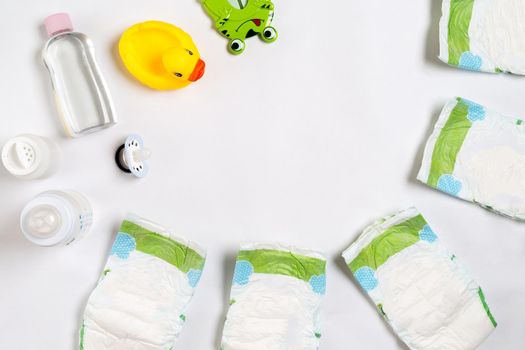 Babies goods diaper, baby powder, cream, shampoo, oil on white background with copy space. Top view or flat lay. Maternity concept