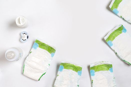 Babies goods diaper, baby powder, cream, shampoo, oil on white background with copy space. Top view or flat lay. Maternity concept