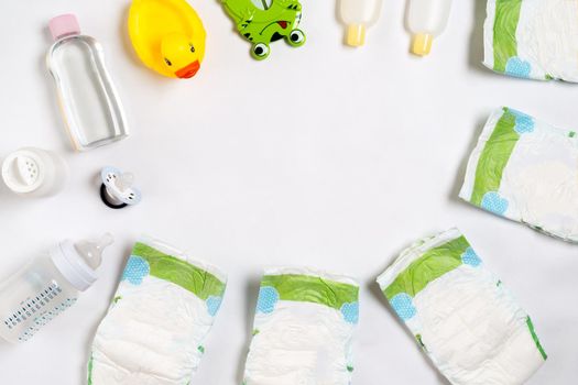 Babies goods diaper, baby powder, cream, shampoo, oil on white background with copy space. Top view or flat lay. Maternity concept