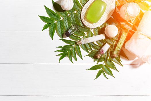 Spa set with towel and soap on white wooden background with green leaves. Top view. Copy space. Still life. Mock-up. Flat lay. Sun flare