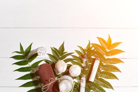 Spa set with towel and soap on white wooden background with green leaves. Top view. Copy space. Still life. Mock-up. Flat lay. Sun flare