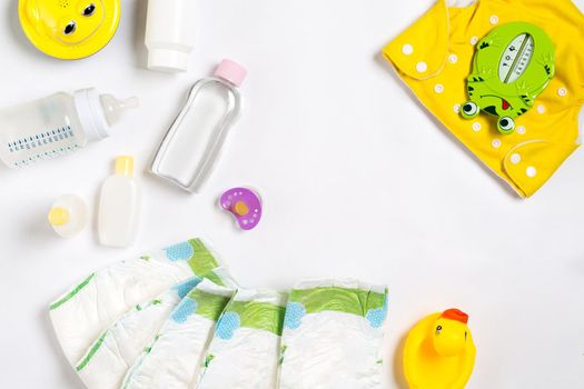 Babies goods diaper, baby powder, cream, shampoo, oil on white background with copy space. Top view or flat lay. Maternity concept