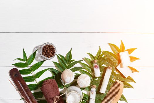 Spa set with towel and soap on white wooden background with green leaves. Top view. Copy space. Still life. Mock-up. Flat lay. Sun flare