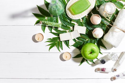 Spa set with towel and soap on white wooden background with green leaves. Top view. Copy space. Still life. Mock-up. Flat lay