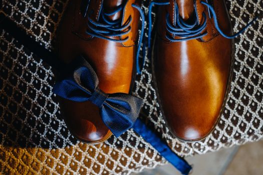 Close-up of a blue bow tie on brown men's shoes.Morning of the groom.