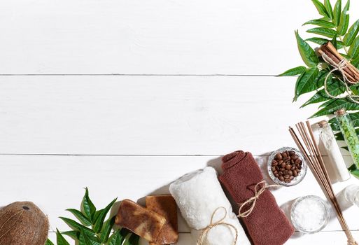 Spa set with towel and soap on white wooden background with green leaves. Top view. Copy space. Still life. Mock-up. Flat lay