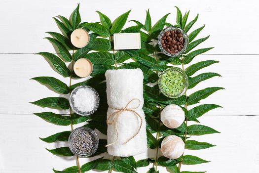 Spa set with towel and soap on white wooden background with green leaves. Top view. Copy space. Still life. Mock-up. Flat lay