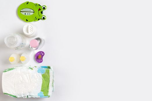 Babies goods diaper, baby powder, cream, shampoo, oil on white background with copy space. Top view or flat lay. Maternity concept