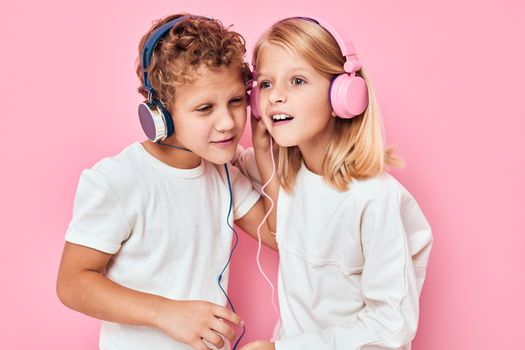 Stylish little boy and cute girl listening to music pink color background. High quality photo