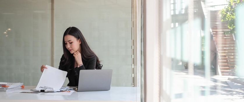 Crop shot of business asian woman investment consultant analyzing company annual financial report balance sheet statement working with documents graphs.