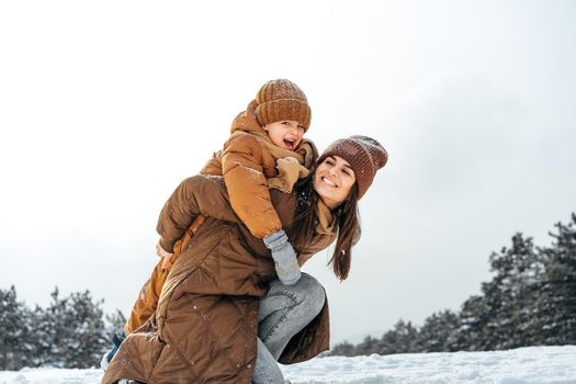 Woman with a little son on a winter hike in the snowy forest together