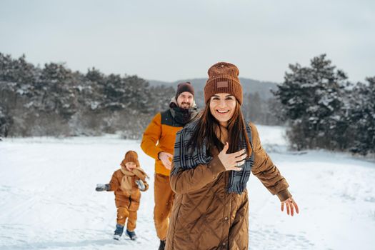 Happy family having a walk in winter outdoors in snow forest