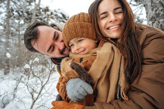 Portrait of happy family in winter clothes in snowy forest