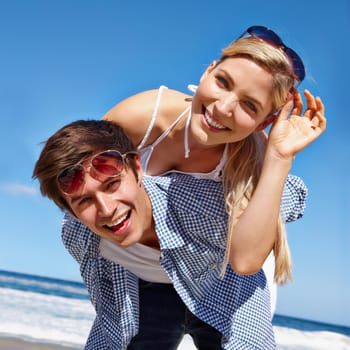 Shot of a happy young couple enjoying a piggyback ride at the beach.
