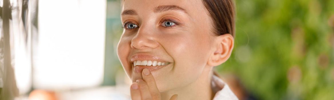 Closeup portrait of natural young woman with beautiful smile and perfect skin having beauty routine in the bathroom. Spa and wellness concept