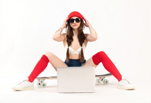 the girl in a red hat and red socks is sitting on a longboard with a laptop on a white background