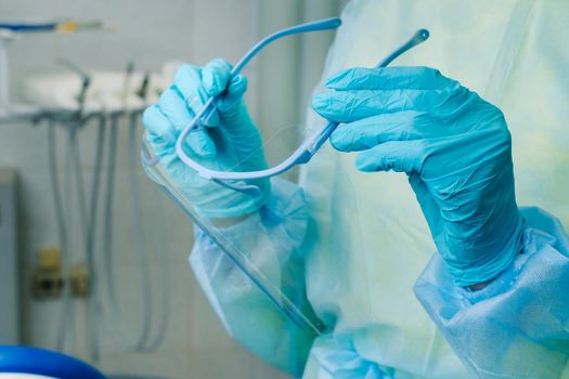 close up of a dentist's hands holding a protective plastic screen in his office.