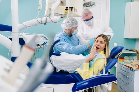 The dentist shows the details of the X-ray to his colleague, the patient is surprised by what is happening.