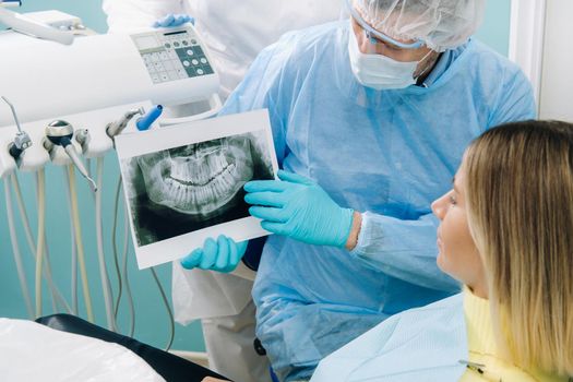 The dentist shows the details of the X-ray to his patient in the doctor's office.