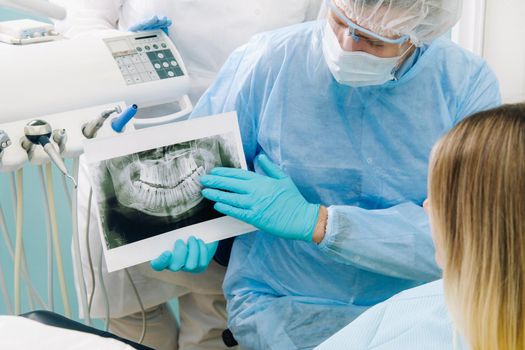 The dentist shows the details of the X-ray to his patient in the doctor's office.